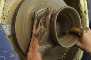 Mani che modellano un vaso di ceramica ancora fresco